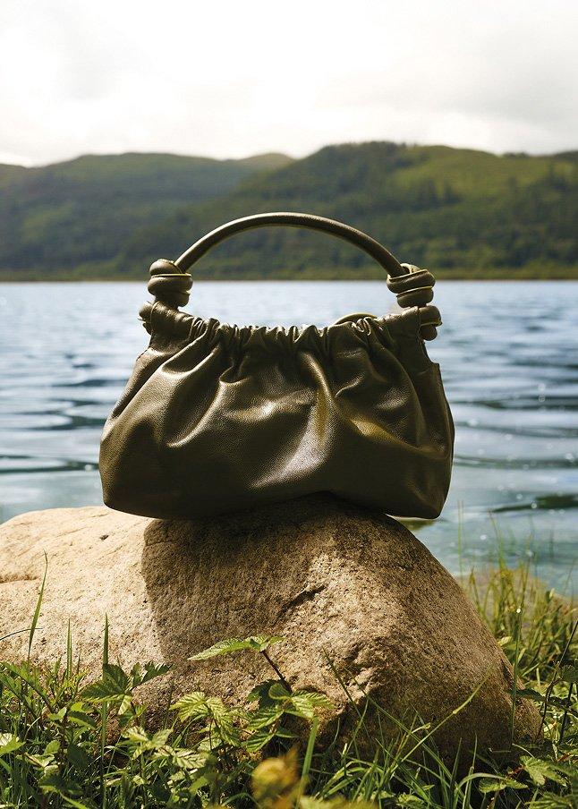 a purse sitting on top of a rock by a body of water