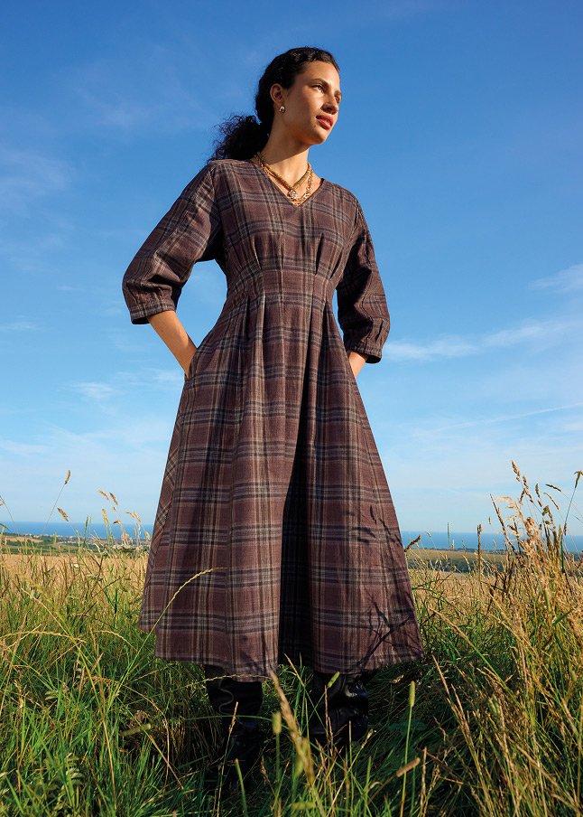 a woman standing in a field with a dress on