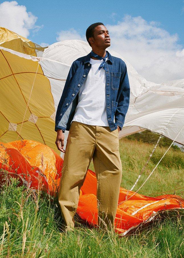 a man standing in a field next to a parachute