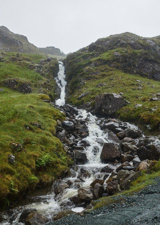 a small stream of water flowing down a rocky hillside