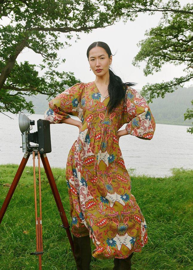 a woman standing in front of a camera with a tripod