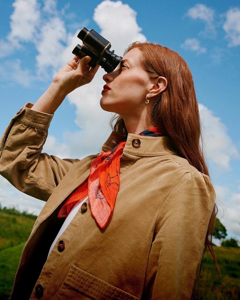 woman looking through binoculars at a hillside