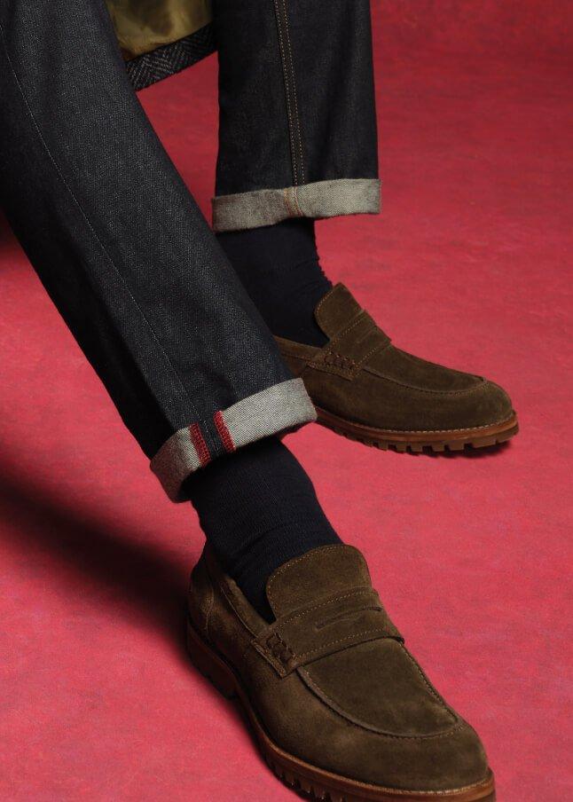 a person wearing brown shoes and jeans sitting on a chair