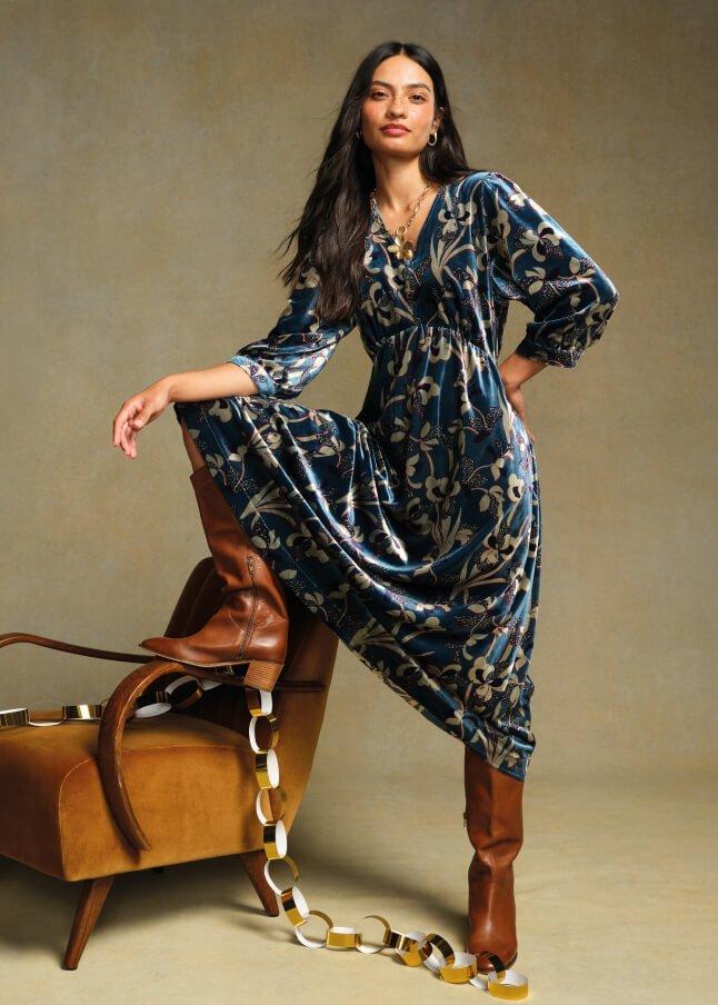 a woman in a blue dress and boots posing on a chair