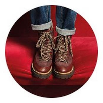 a person wearing brown boots and jeans sitting on a red couch