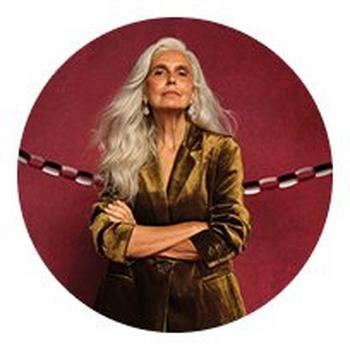 a woman with long white hair and a gold jacket