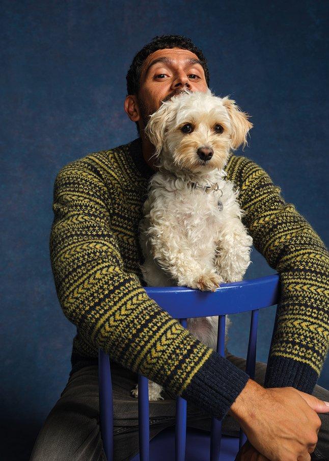 a man sitting on a chair with a dog on his lap