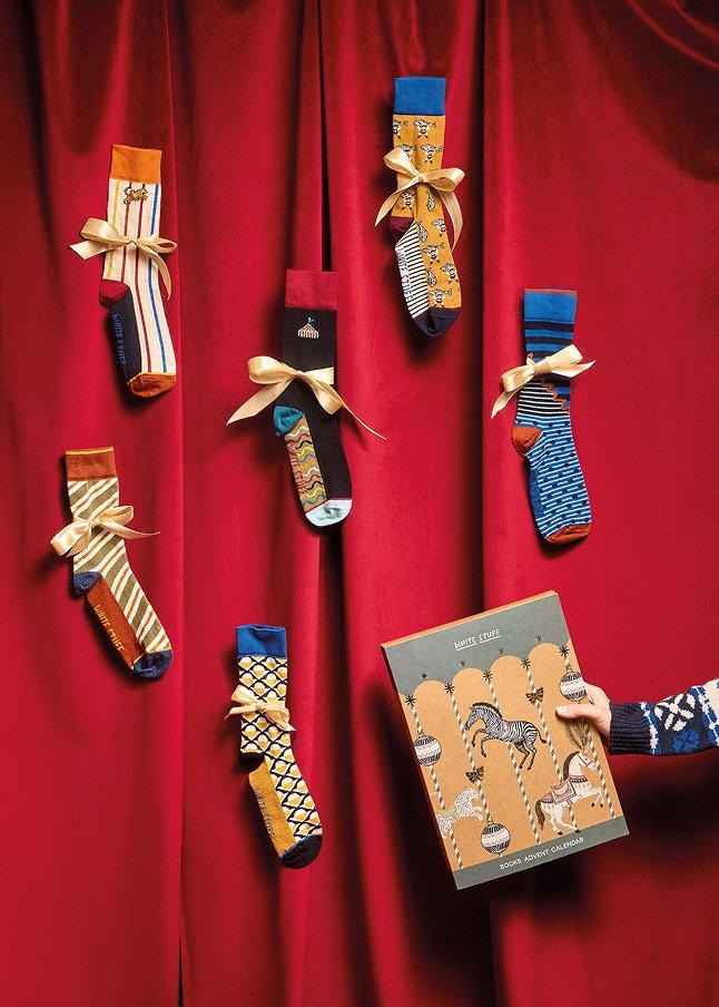 a person holding a box with socks on it and a red curtain