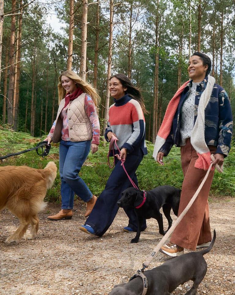 a photo of a group of women wearing White Stuff clothing in a forest walking their dogs