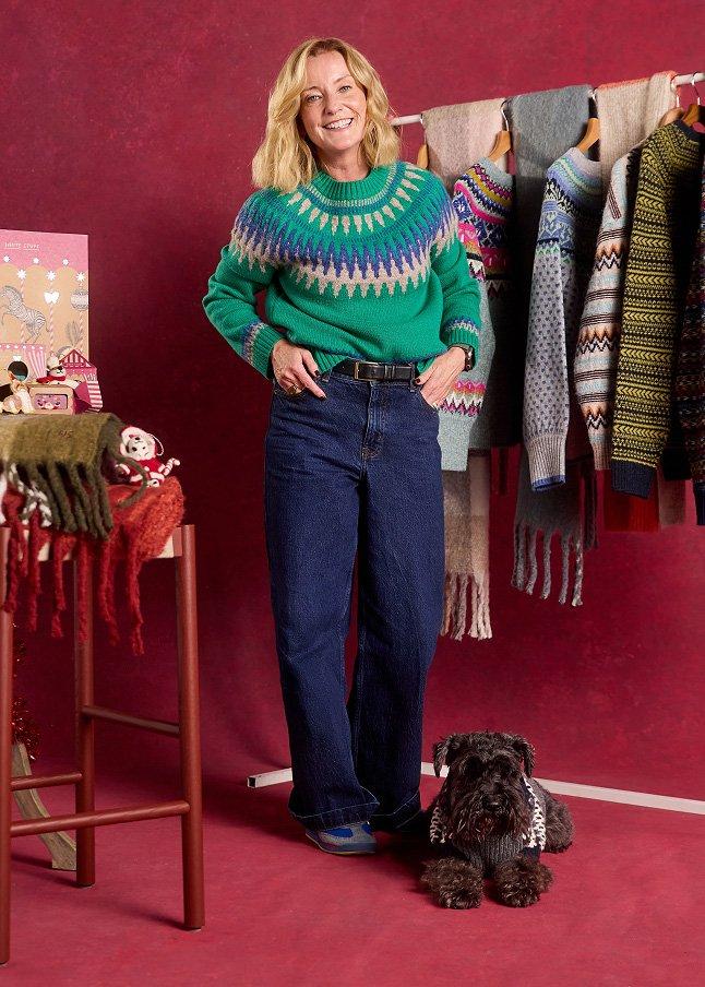 a woman standing next to a dog in front of a rack of clothes