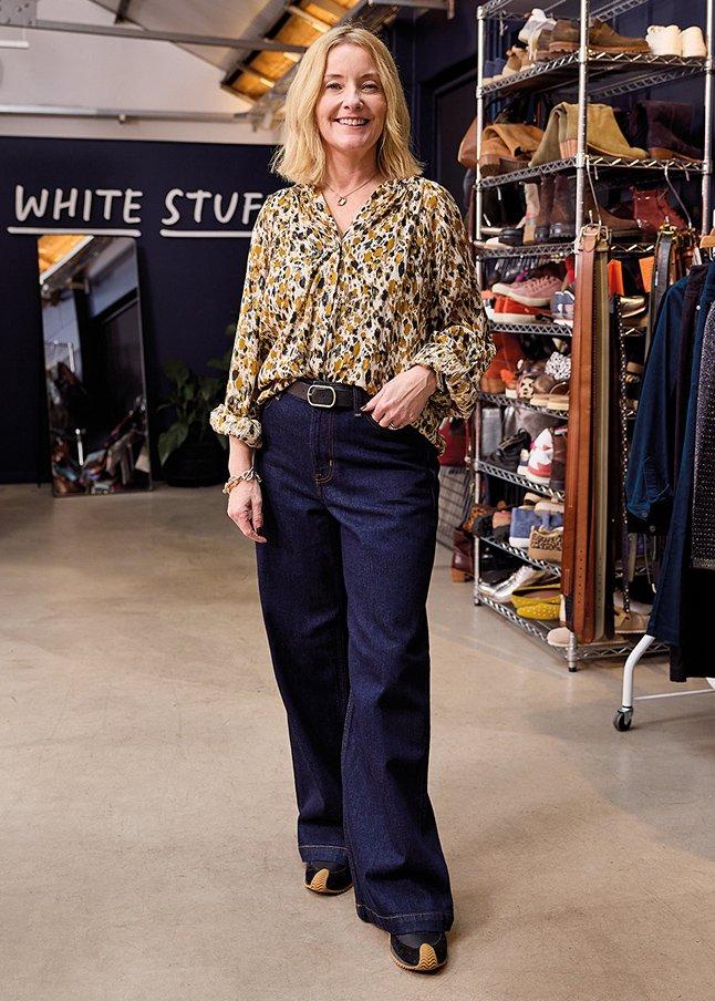 a woman standing in front of a clothing store wearing jeans and a shirt