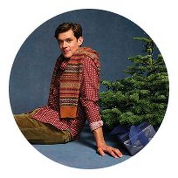 a man sitting on a chair next to a christmas tree