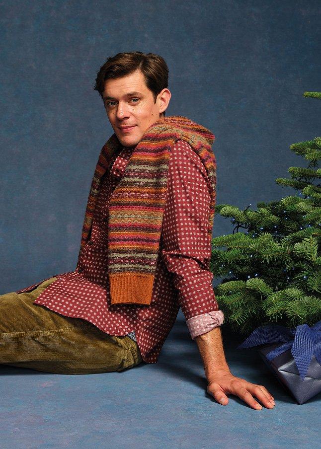 a man sitting next to a christmas tree