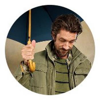 a man holding an umbrella in his hand and looking at the camera