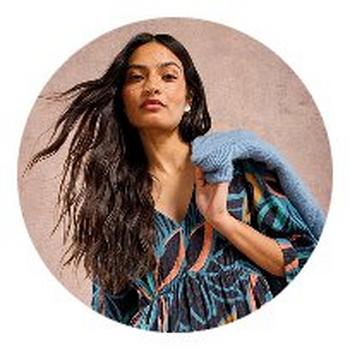 a woman in a blue dress with a sweater on her shoulder