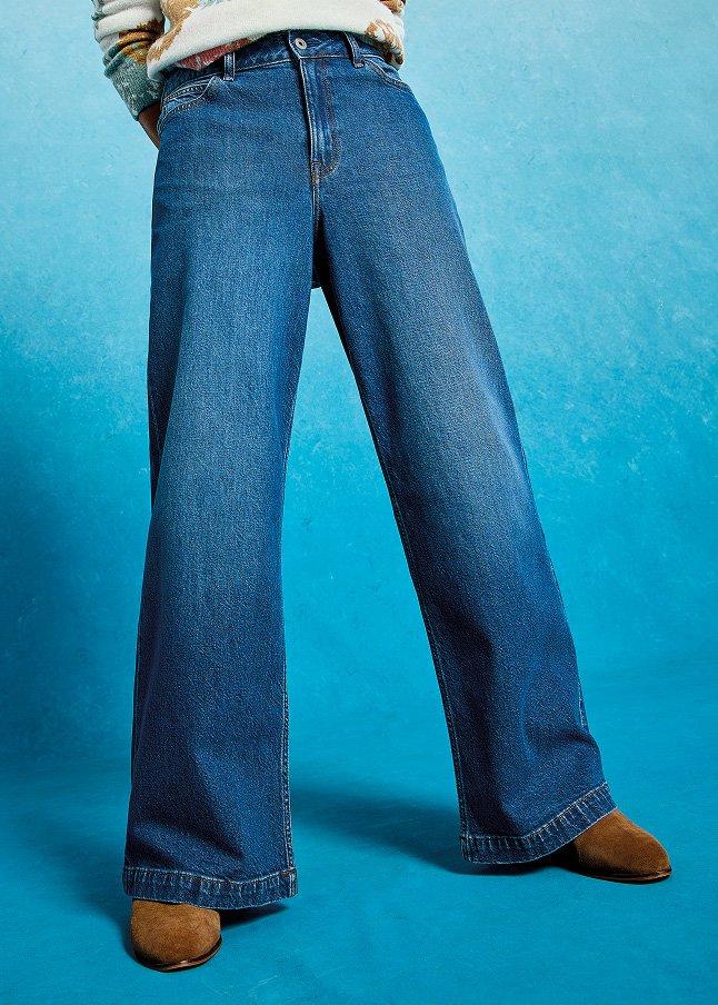 a man in a sweater and jeans posing for a picture