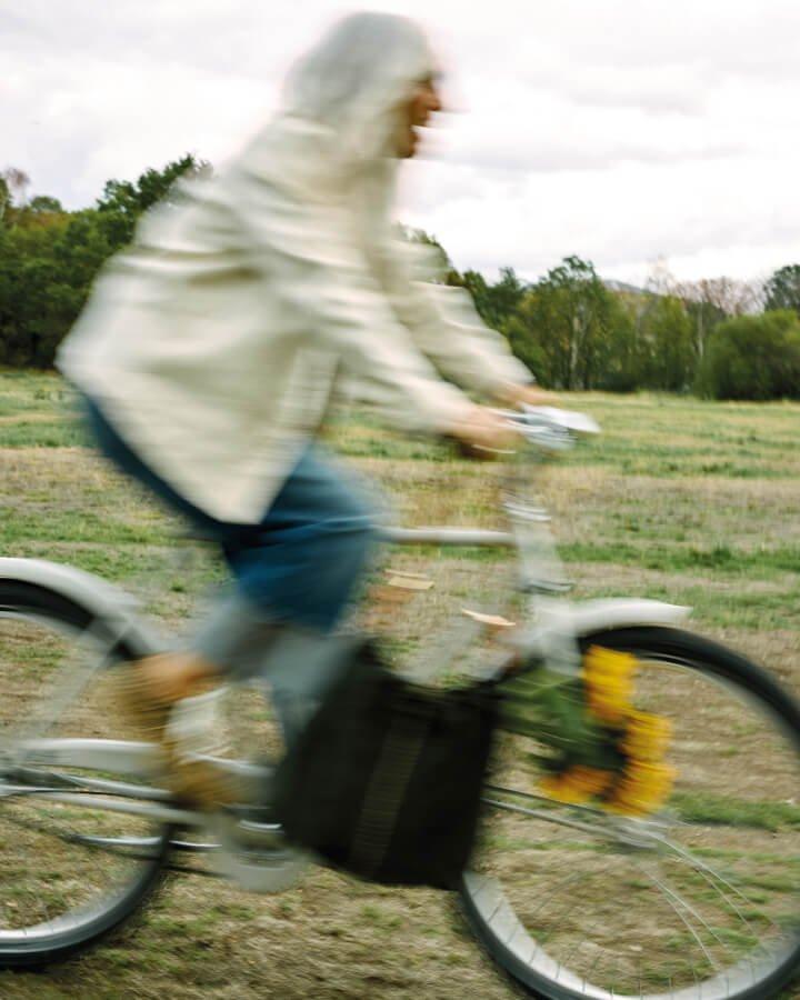 a person riding a bike in a field with a bag on the back