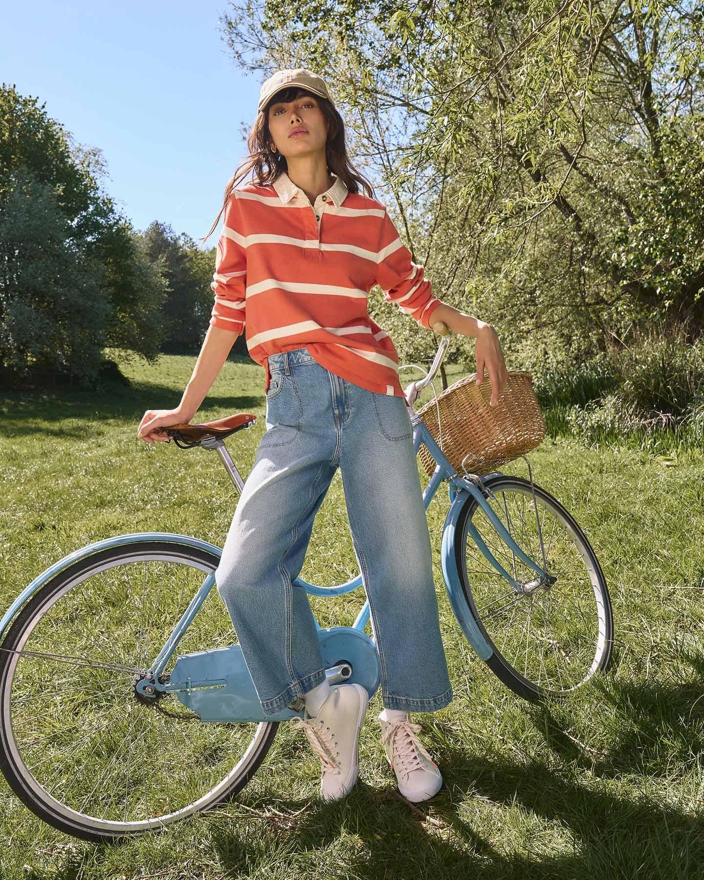 a woman in striped shirt leaning against a blue bike