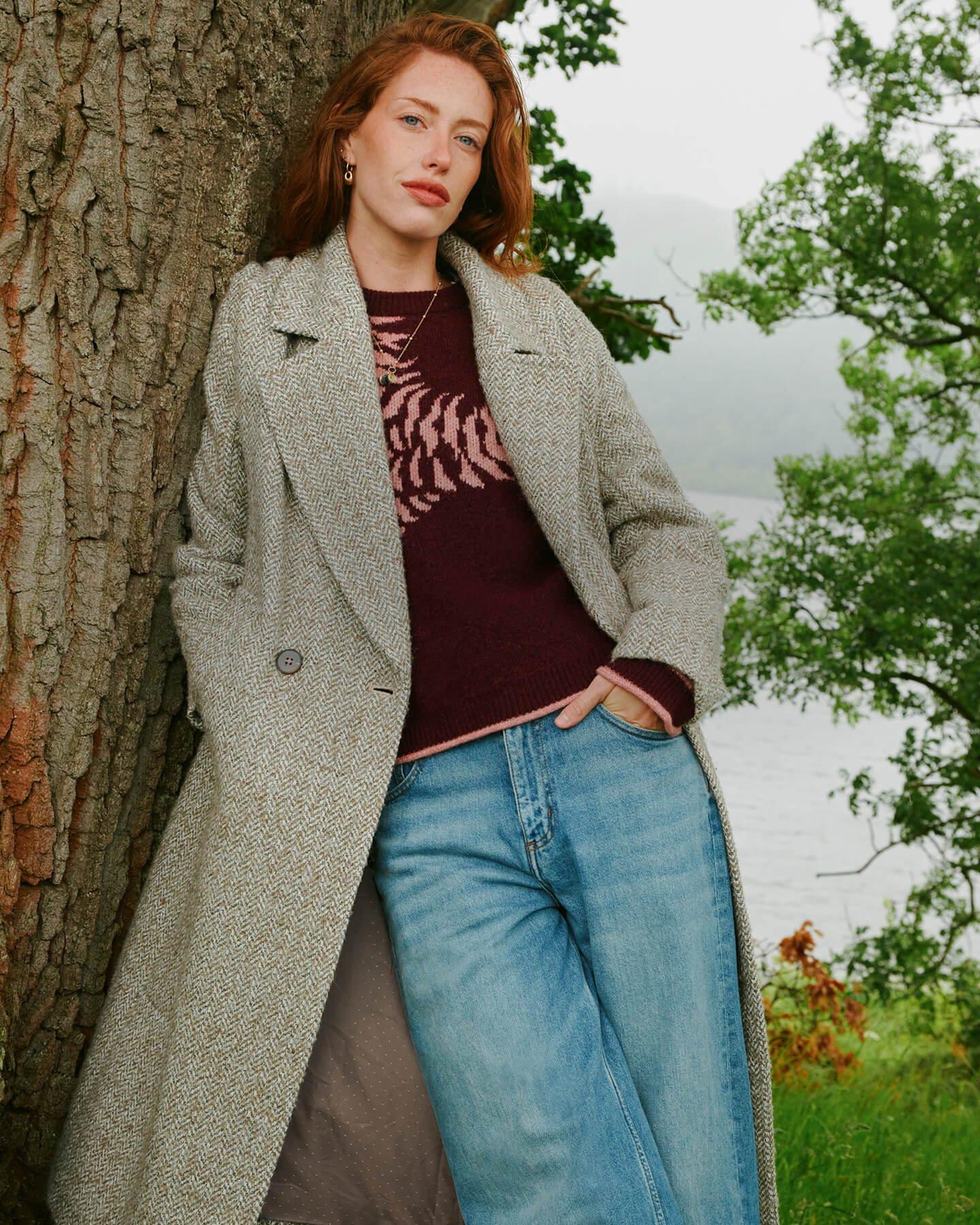 a woman leaning against a tree with her arms crossed
