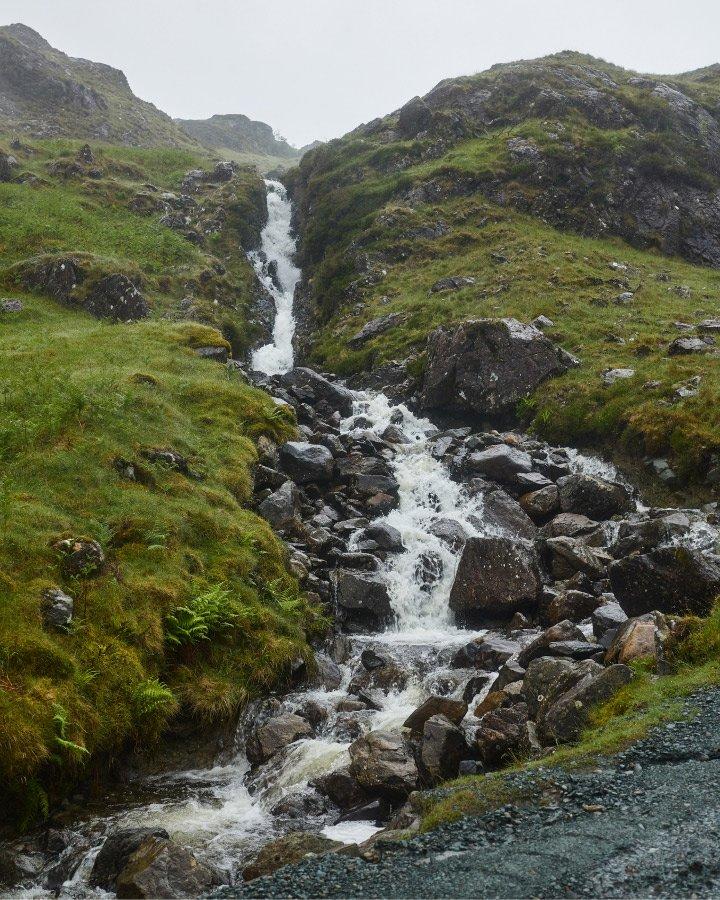 a small stream of water flowing down a rocky hillside