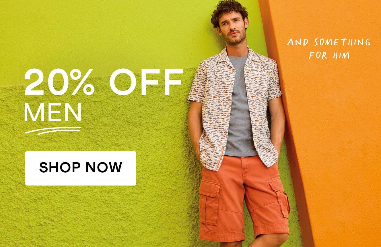 A man in a printed short sleeve shirt and orang shorts standing against a colourful wall, with the text "20% off men", Click here to shop menswear