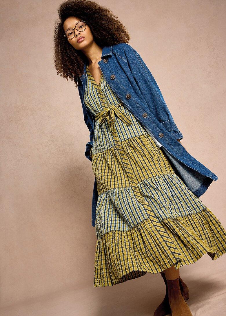 a woman in a dress and denim jacket posing for a photo