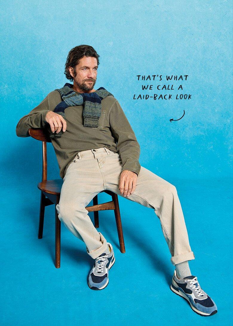 a man sitting on a chair with a beard and a sweater