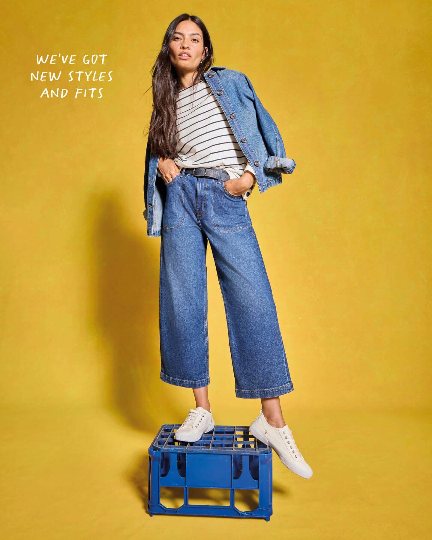 Woman in denim jacket, striped t-shirt, cropped jeans and white trainers.