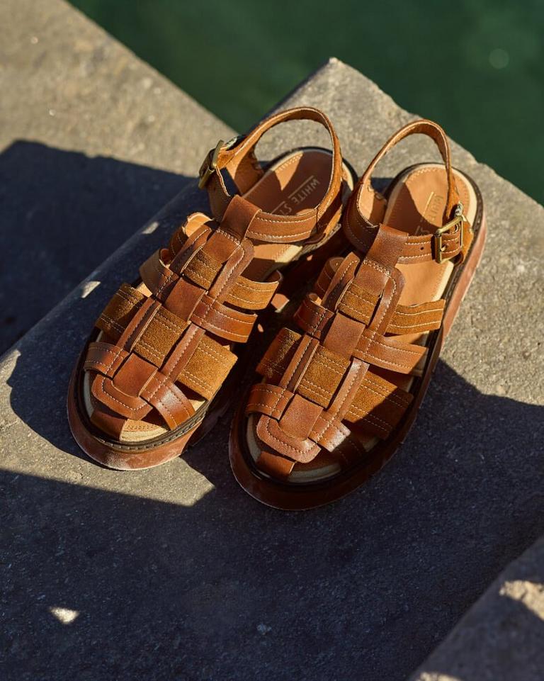 a pair of brown sandals sitting on a ledge near a body of water
