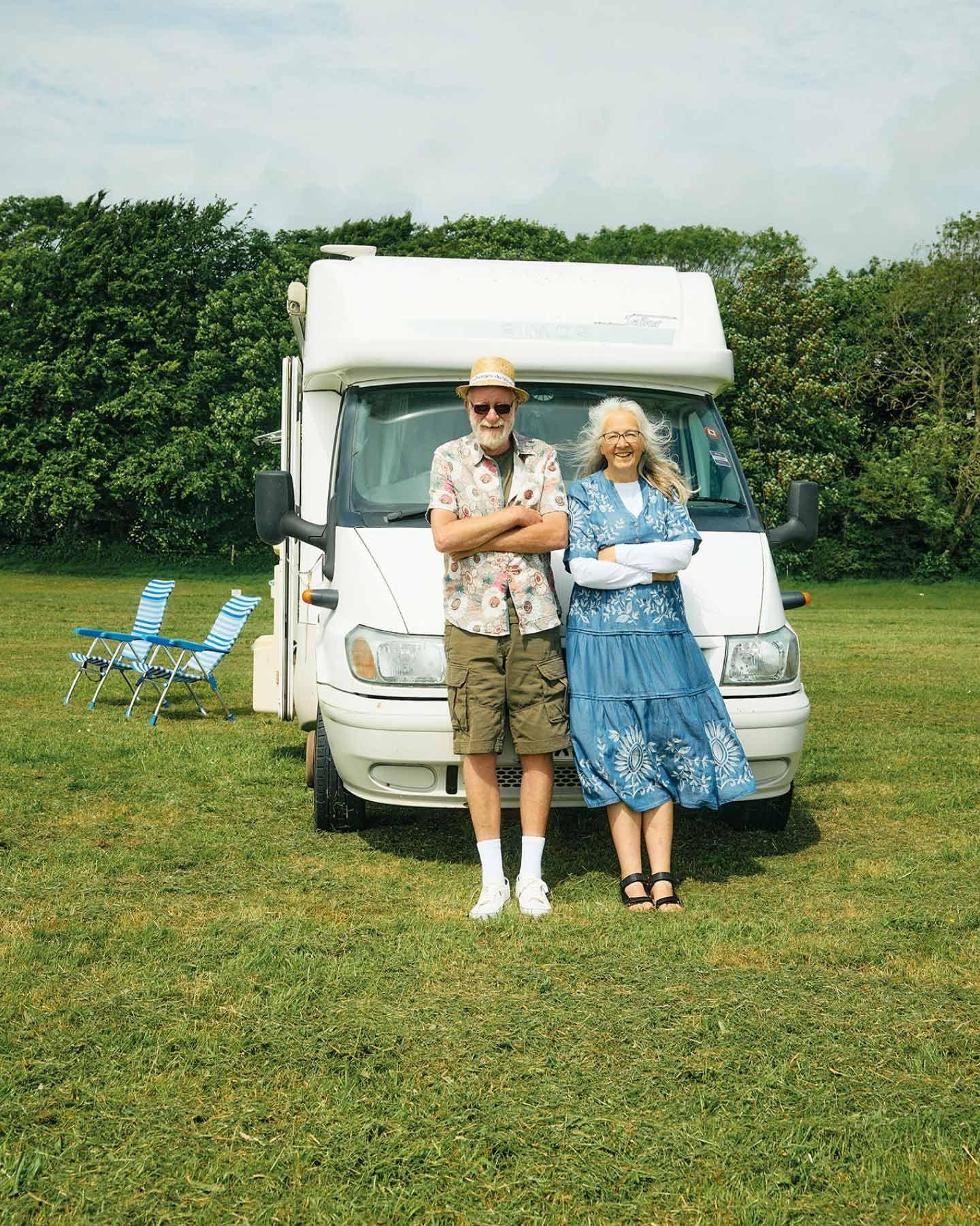 A men wearing green shorts and a woman wearing a blue dress in front of their camper van