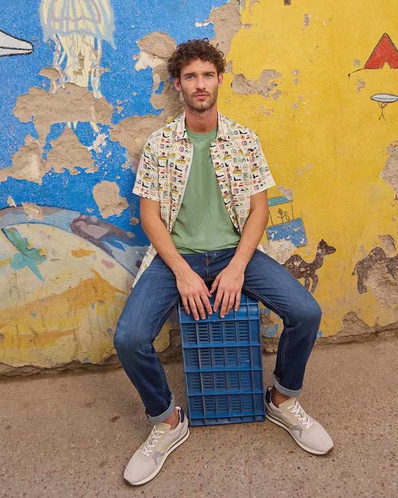 a man sitting on a blue crate in front of a wall wearing the Finsbury printed shirt