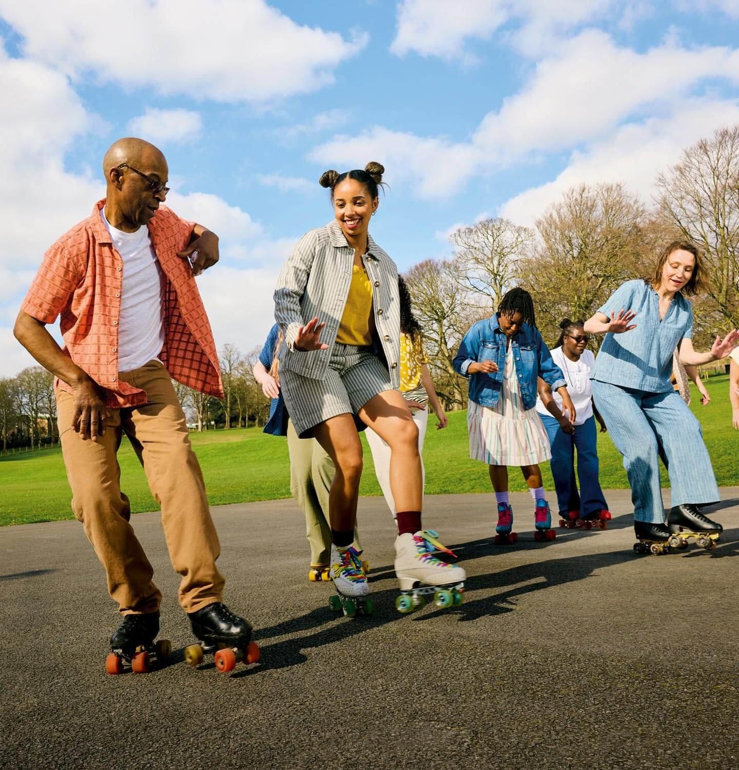 A group of people on roller skates in a park wearing clothes from the White Stuff Summer Collection.