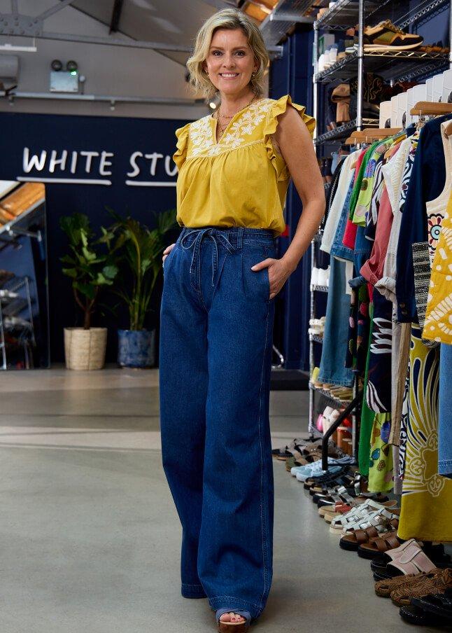 a woman standing in front of a rack of clothes