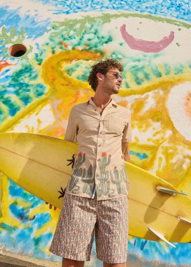 a man holding a surfboard in front of a colorful mural