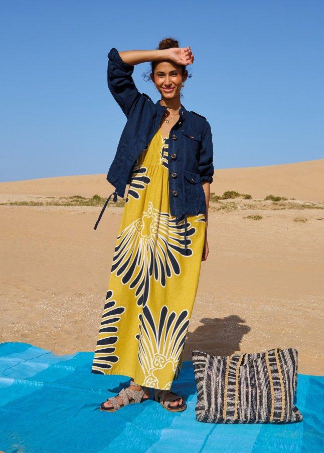 a woman in a yellow dress standing on a blue blanket