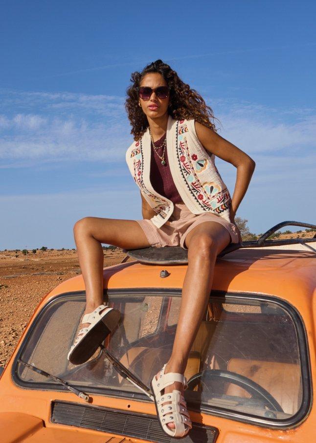 a woman sitting on top of a car in the desert