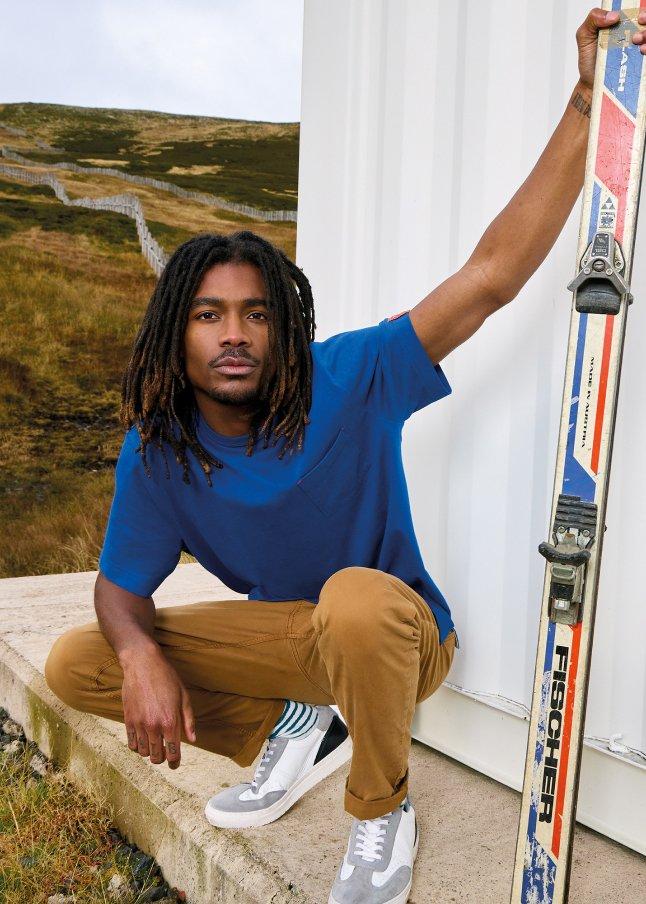 a man with dreadlocks holding a pair of skis on a ledge