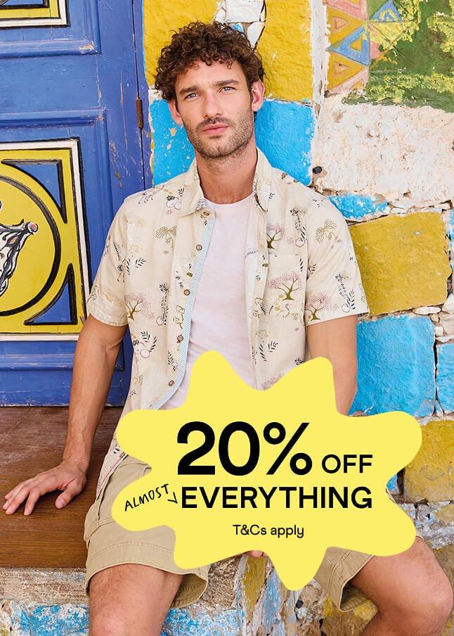 a man sitting on a bench with a sign that says 20 % off everything