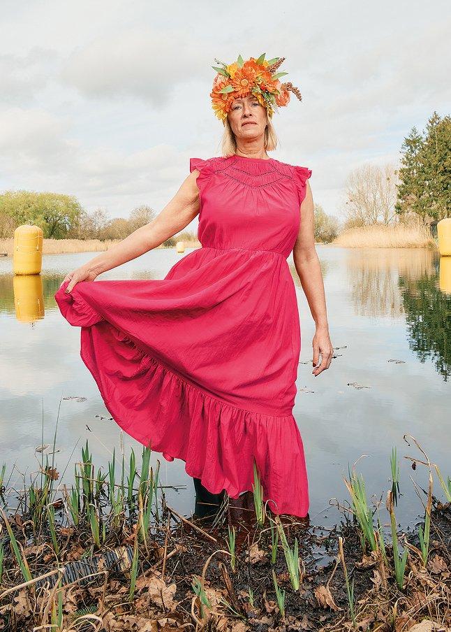 a woman in a pink dress standing in a swamp