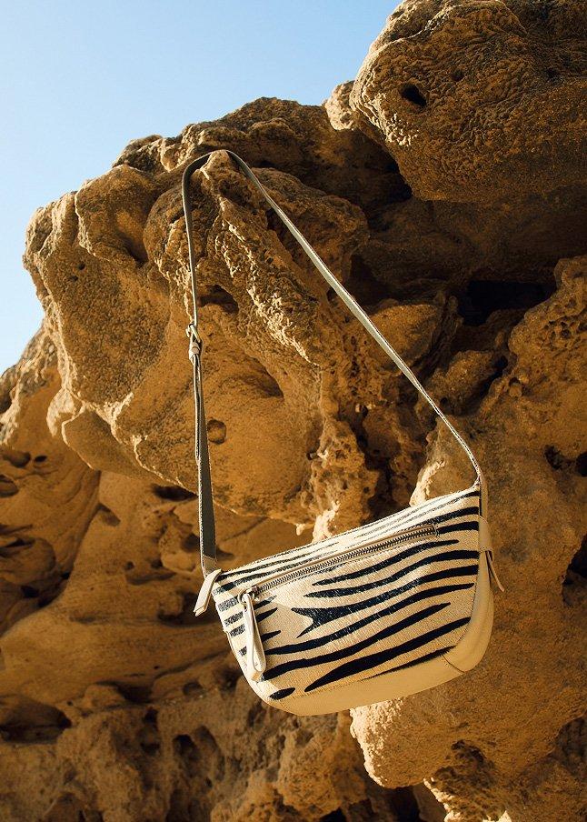 a white and black purse hanging from a rock formation