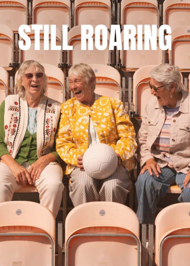 three women sitting in a row of empty seats with a ball