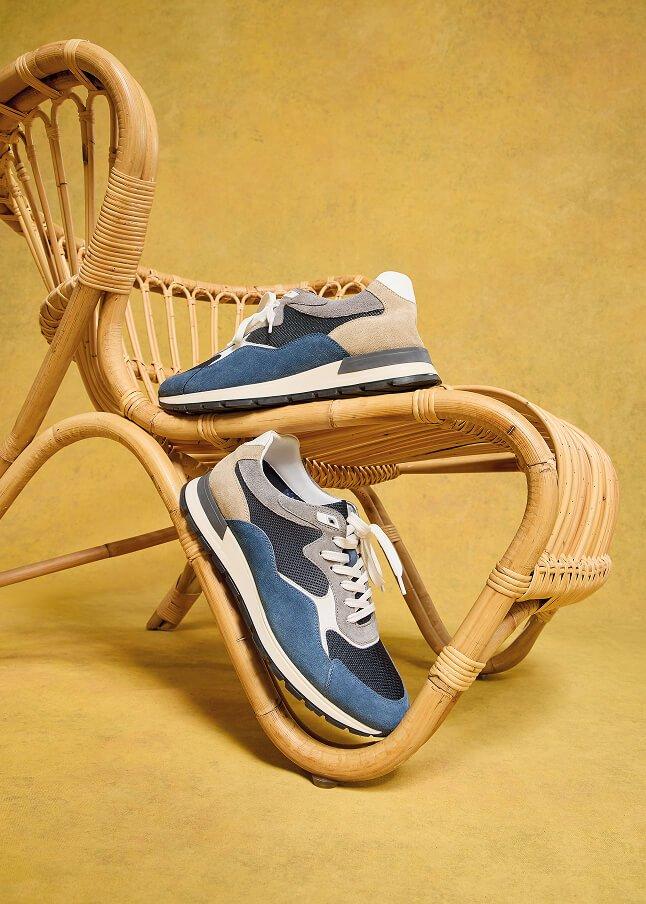 two pairs of shoes are sitting on the ground next to a rock wall