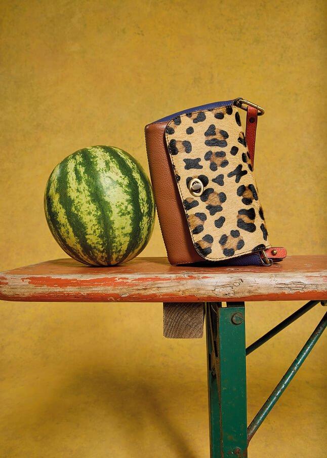 a watermelon and a purse on a table next to a wall