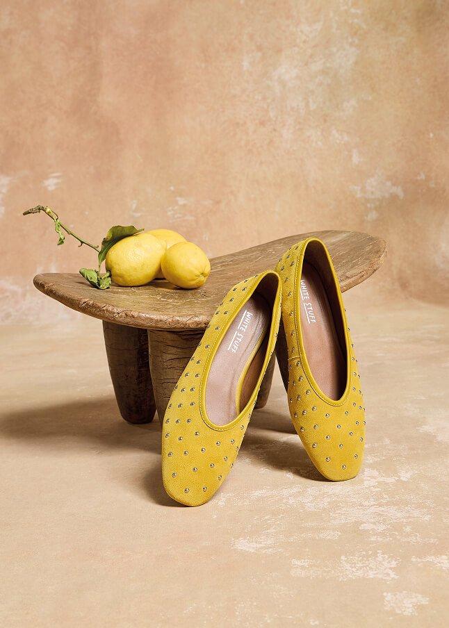 a pair of yellow shoes sitting on a wooden bench with lemons