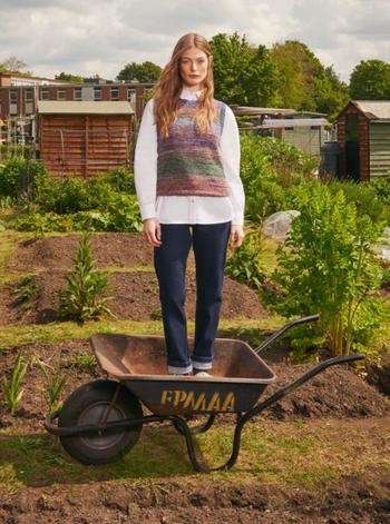 a woman standing in a wheelbarrow in a garden