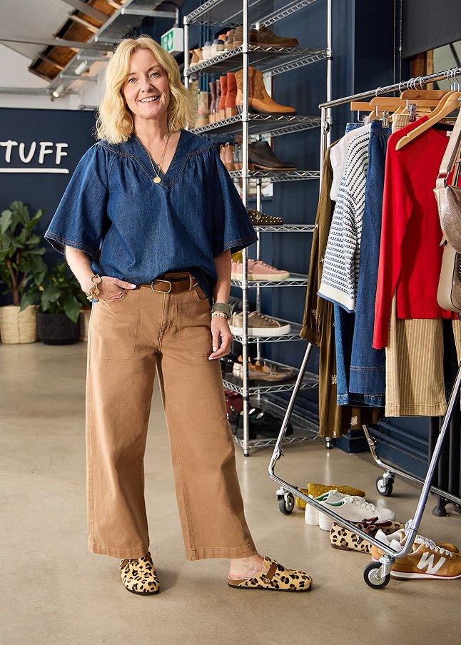 a woman standing in front of a rack of clothes