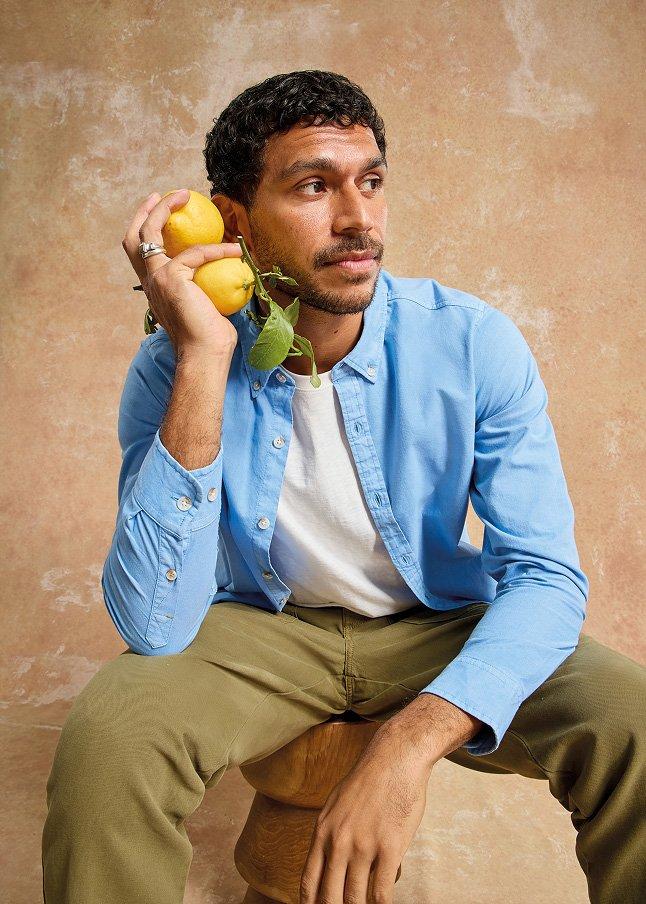 a man sitting on a stool holding a lemon in his hand