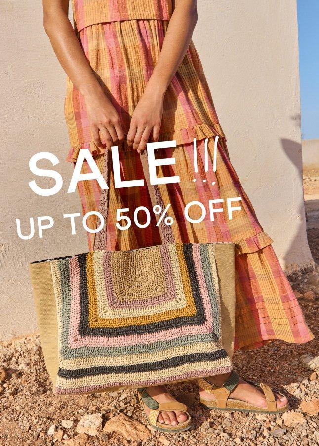 a woman holding a bag with the words sale up to 50 % off