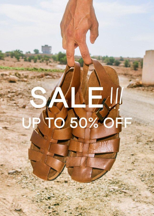 a hand holding up a pair of sandals with the words sale up to 50% off